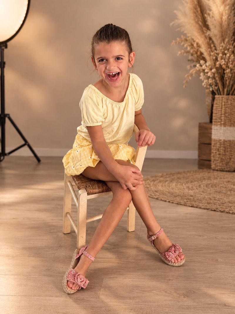 Alma qui rit aux éclats, assise sur une petite chaise